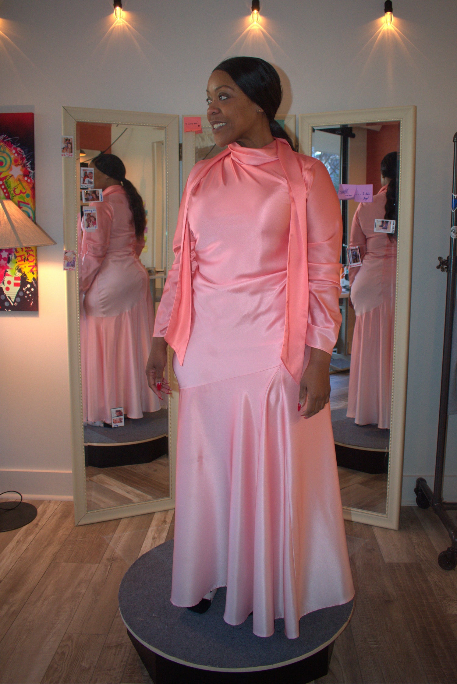 Woman in a pink dress standing in front of a mirror with a blurred background